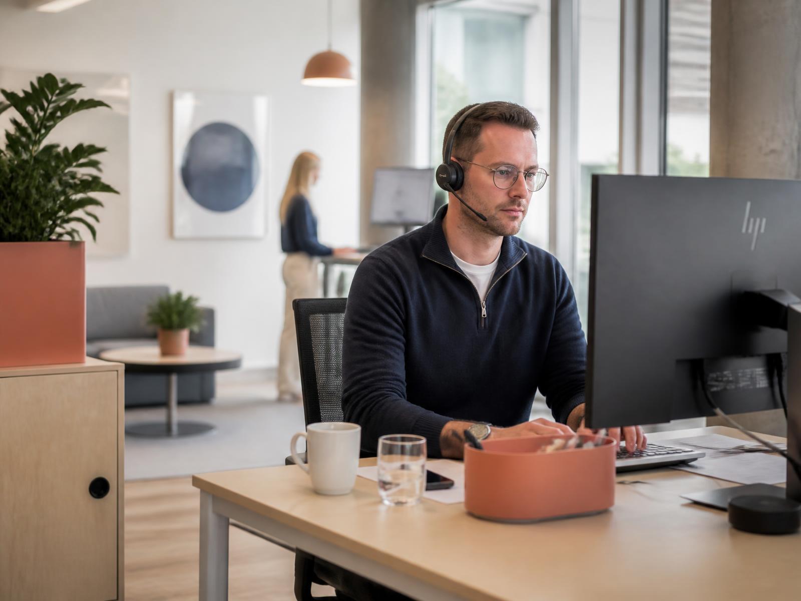 Säljare med headset i ett ljust kontor som ringer och bokar möten för kunder